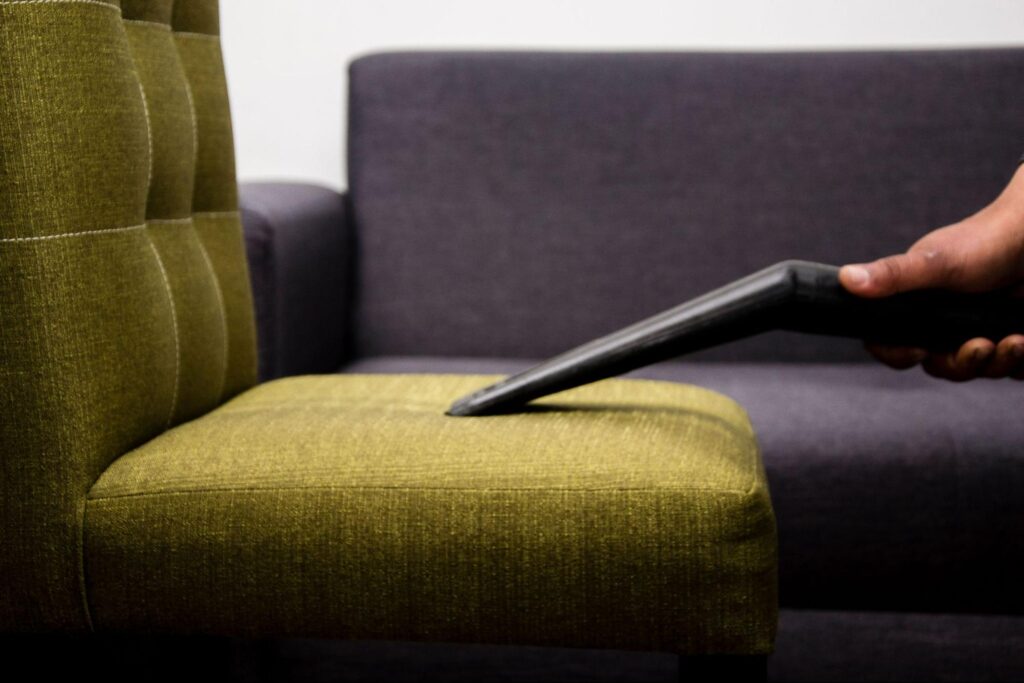 Sofa upholstery being vacuumed during a detailed living room deep clean.